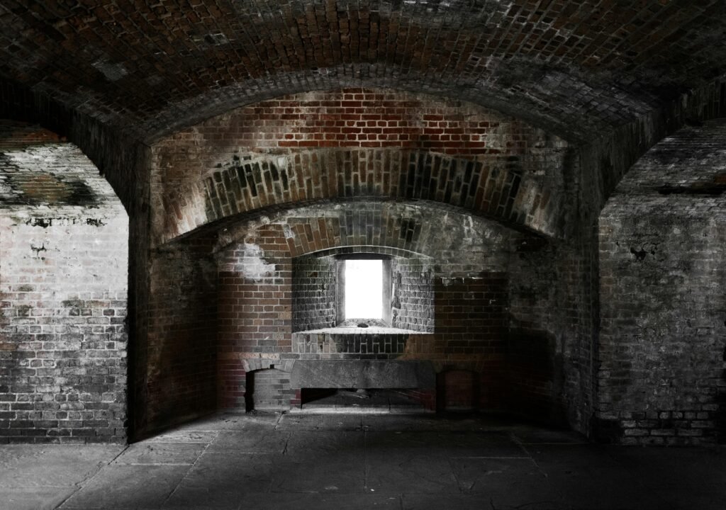 A moody view of an abandoned brick archway interior in Key West, showcasing symmetry and gothic elements.