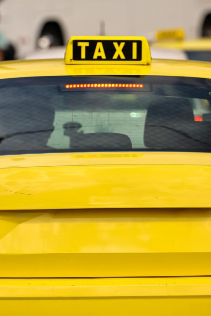 Close-up of a yellow taxi in Athens, Greece, highlighting the bright sign and urban setting.