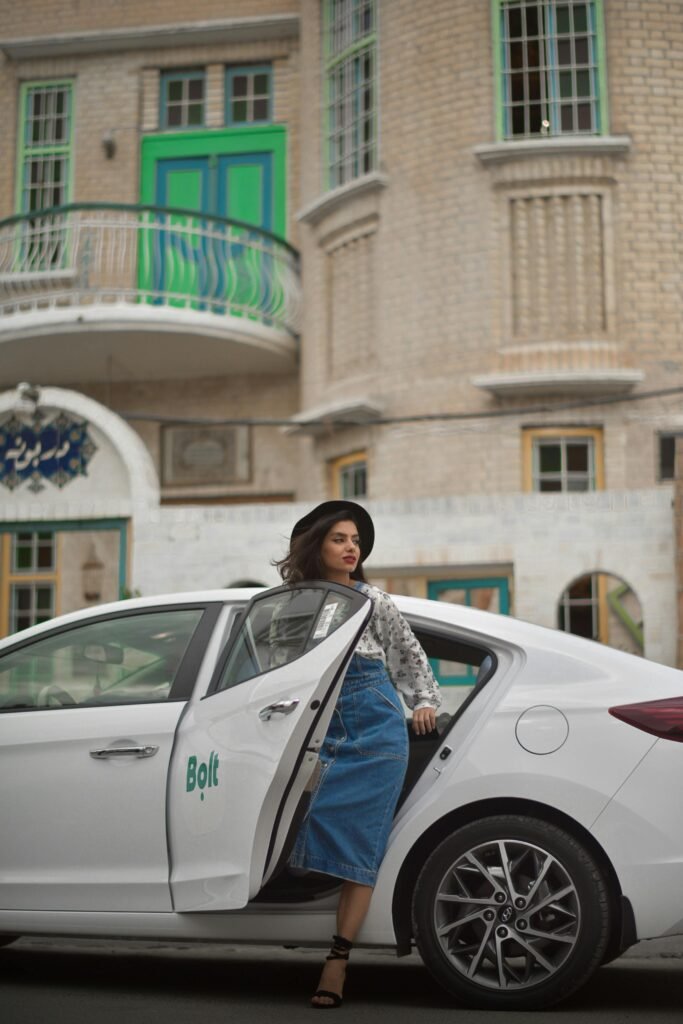 A fashionable woman steps out of a Bolt ride-share vehicle in an urban setting, showcasing modern city life.